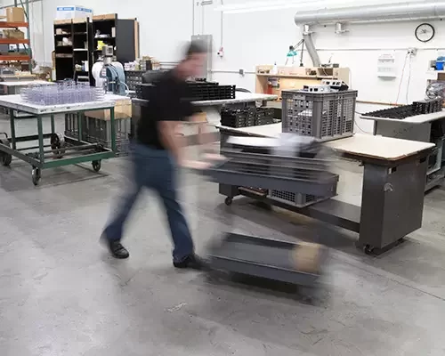 Envision team member pushing a cart of parts across the production floor