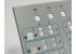 Close-up of a gray control panel with printed MTS labels, blue outlines and red and green lock icons around its cutouts
