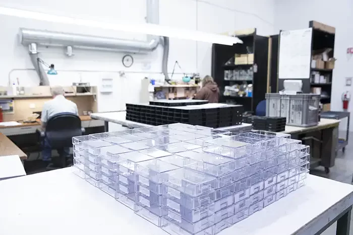 Rows of clear plastic enclosures on a workbench in the Envision shop